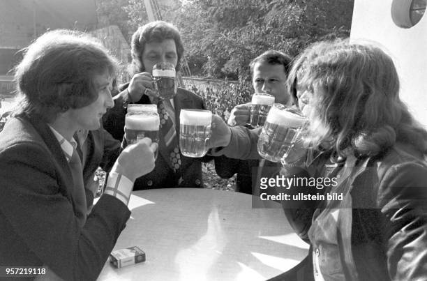 Junge Männer in Anzug und Krawatte prosten sich zu und trinken ihr Bier vor einem Lokal in der Schönhauser Allee, undatierte Aufnahme von 1976 aus...