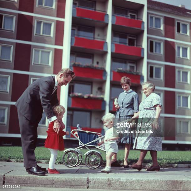 Eine junge Familie mit zwei Kindern, Kinderwagen und eine alte Frau vor neuen Wohnungen, aufgenommen 1963. Schon in den 1950er Jahren entwickelte...