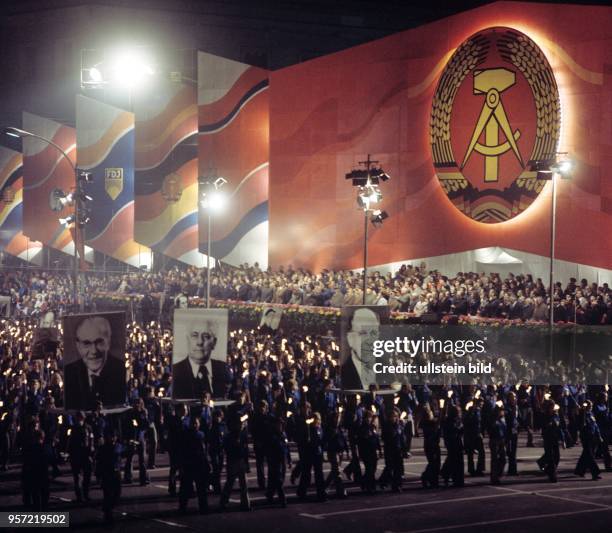 Mit Bildnissen von Otto Grotewohl, Wilhelm Pieck und Walter Ulbricht, die 1949 zu den Gründungsvätern der DDR gehörten, und Fackeln ziehen FDJler zur...