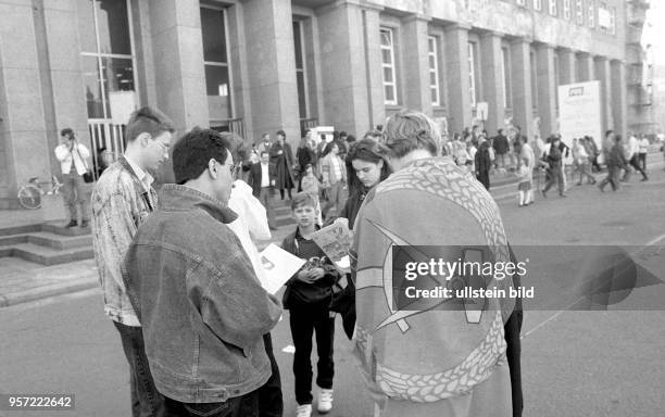 Junge Menschen stehen im März 1990 mit einer Fahne der DDR vor dem ehemaligen Sitz des Zentralkommittees der Sozialistischen Einheitspartei in Berlin...