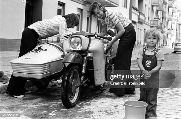 Ein junges Paar beim Waschen ihres Motorradgespannes, aufgenommen im August 1977 im Berliner Stadtbezirk Prenzlauer Berg. Auch der Nachwuchs wird zum...