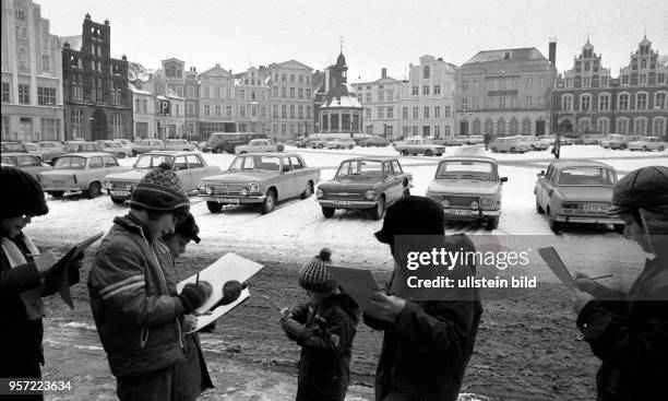 Schulkinder zeichnen den winterlichen Marktplatz der Hansestadt Wismar mit seinen historischen Bürgerhäusern wie der Gaststätte "Alter Schwede" sowie...