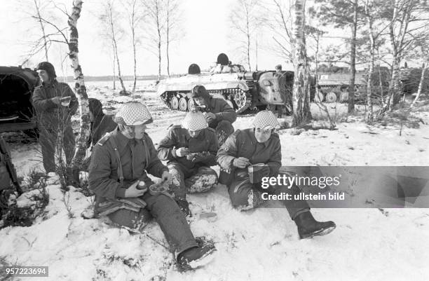 Infanteristen der Nationalen Volksarmee im winterlichen Gelände bei der Verpflegung im Rahmen einer Übung, undatiertes Foto von 1981 bei Torgelow.