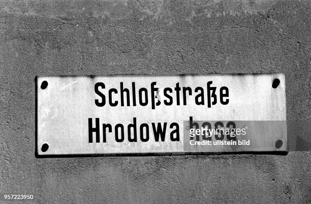 In deutscher und sorbischer Sprache steht das Wort Schloßstraße an einem Straßenschild an einer alten Fassade in der Altstadt von Bautzen,...
