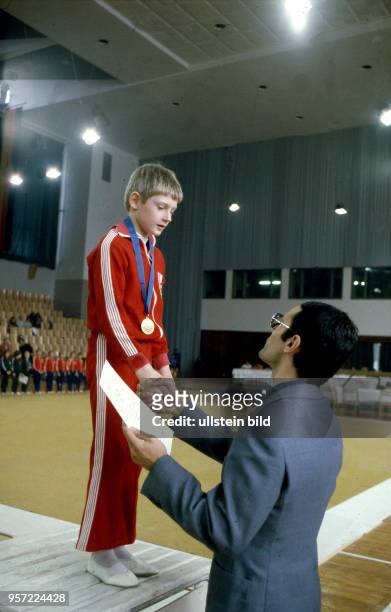 Ein junger Sportler auf dem Siegerpodest wird mit Medaille und Urkunden bei einer Siegerehrung bei der Kinder - und Jugendspartakiade der DDR 1979 in...