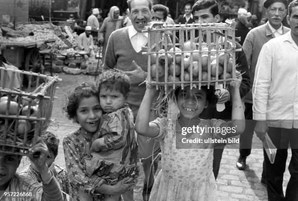 Ein Mädchen trägt einen geflochtenen Korb mit Früchten auf dem Kopf zu einem Verkaufsstand auf einen Basar in Kairo , aufgenommen 1972.