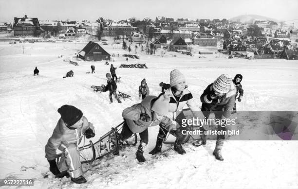 Kinder ziehen ihre Schlitten einen Rodelberg hinauf und freuen sich über den vielen Schnee, aufgenommen 1978 im osterzgebirgischen Altenberg. Sie...