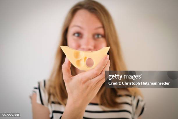 woman holding cheese in front of her face - cheeses stock-fotos und bilder