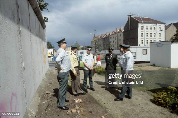 Volkspolizisten aus Berlin-Ost und Polizisten aus Berlin-West sprechen an der Berliner Mauer an der Brunnenstraße miteinandern, undatiertes Foto vom...