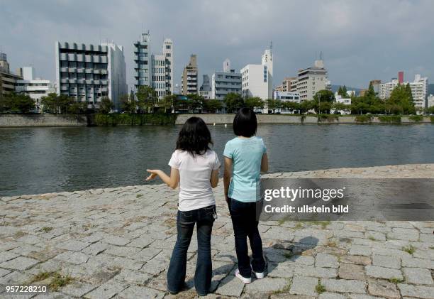 Japan / Hiroshima / Oktober 2009 / Zwei Mädchen betrachten die Neubauten in der Nähe vom Friedenspark am Ufer vom Ota in Hiroshima, aufgenommen im...