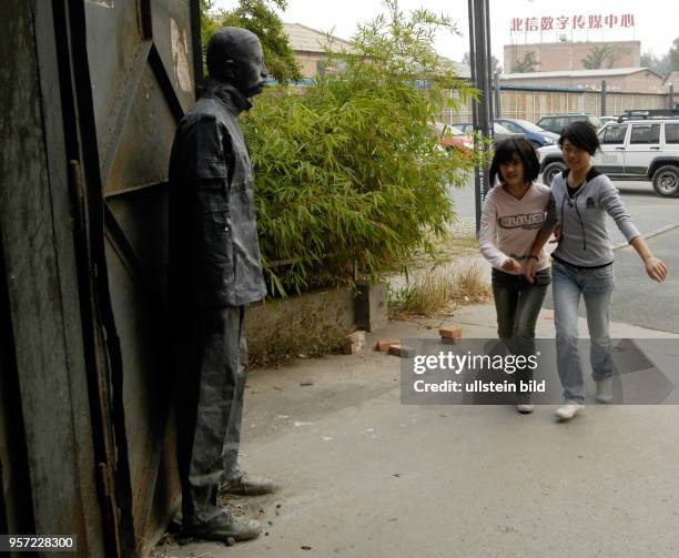 Oktober 2009 / China - Peking / Zwei junge Mädchen kommen in eine Ausstellungshalle vor der eine Figur steht. Kunst spielt in Peking, der Hauptstadt...