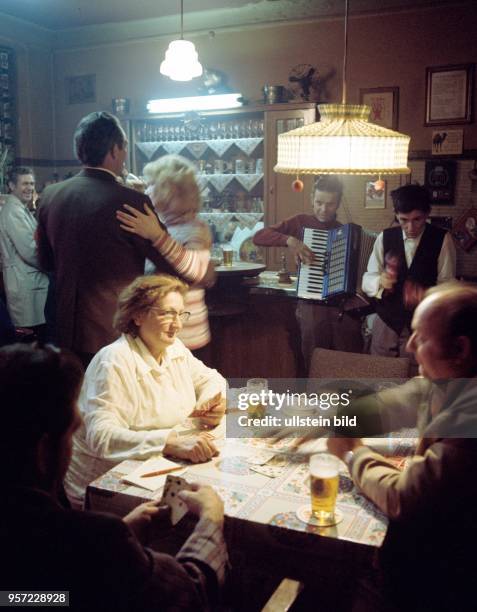 Gäste an einem Tisch in der Kneipe "Zum Löwen" beim Kartenspiel, zwei Musikanten, "Die lustigen Vagabunden", spielen zum Tanz, Gemütlichkeit nach...