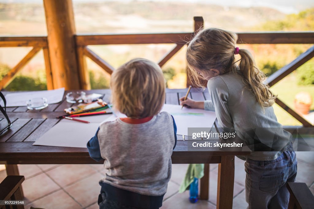 Duas crianças pequenas se divertindo enquanto desenha na varanda.