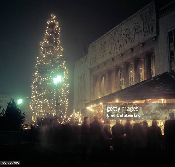 Lichter des Weihnachtsmarktes mit großem Weihnachtsbaum vor der Sporthalle in der Karl_Marx_Allee in Berlin , aufgenommen im Dezember 1963.