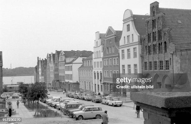 Altbauten prägen das Bild in dieser Straße von Rostock, aufgenommen im 1984. Pkw, zumeist vom Typ Trabant - parken hier am Straßenrand.
