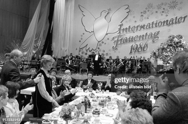 Eine Frau bekommt während der zentralen Frauentags-Feier der DDR in Berlin zur Rede ein Mikrofon gereicht, aufgenommen am . An einem Tisch mit...