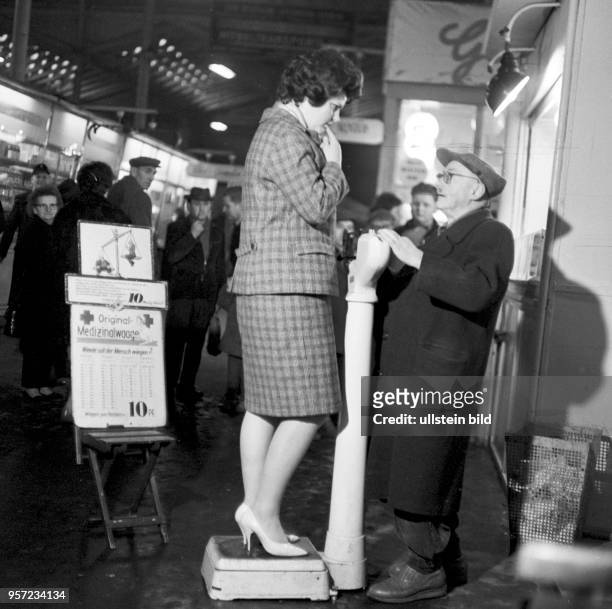 Eine Frau steht in der Ackerhalle in Berlin auf einer "medizinischen Waage" eines ambulanten Dienstleisters und lässt für 10 Pfennig ihr Gewicht...
