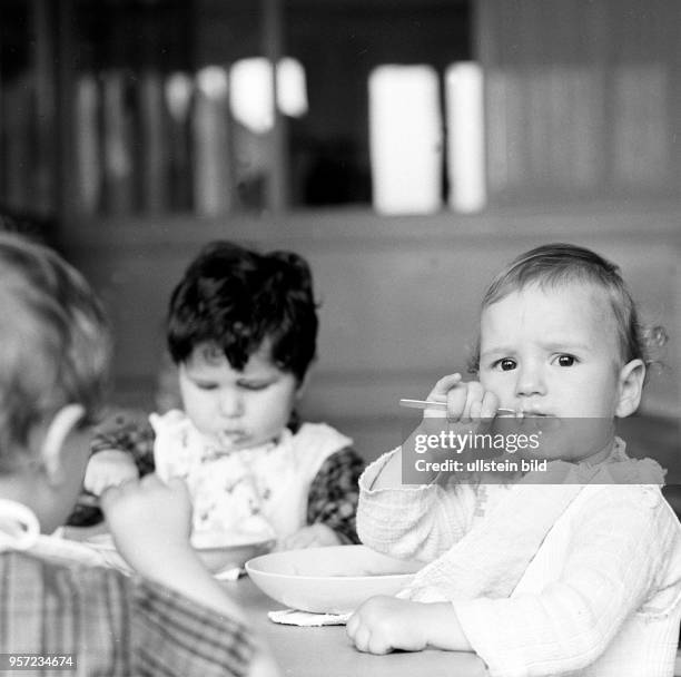 Kinder beim Essen an einem Tisch in einem Kindergarten in Berlin-Treptow, aufgenommen im August 1968.