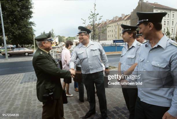 Volkspolizisten aus Berlin-Ost begrüßen einen Kollegen aus Berlin-West an der U-Bahnstation Bernauer Straße, undatiertes Foto vom Juli 1990. Die...