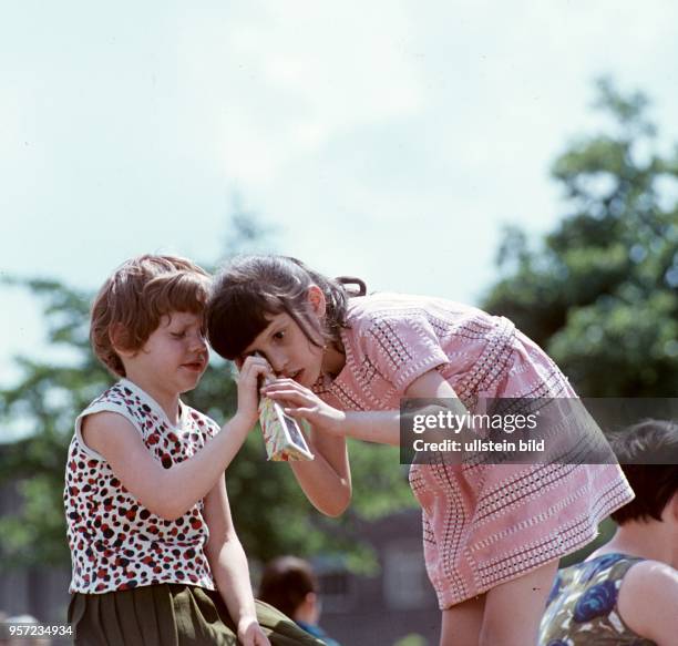 Ein Mädchen betrachtet staunend ein buntes Bild in einem sogenannten Kaleidoskop, ein optisches Kinderspielzeug, aufgenommen im Juli 1967.
