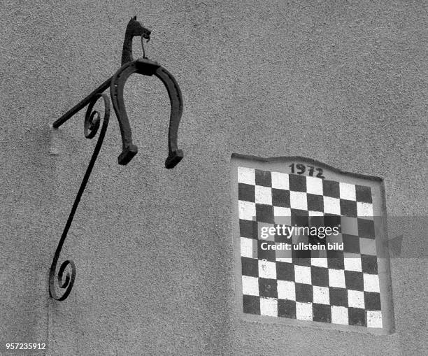 Ein Schachbrett als Wandschmuck neben schmiedeeisernen Zunftzeichen - ein Detail aus dem Schachdorf Ströbeck - hier wird Schach an der Schule...