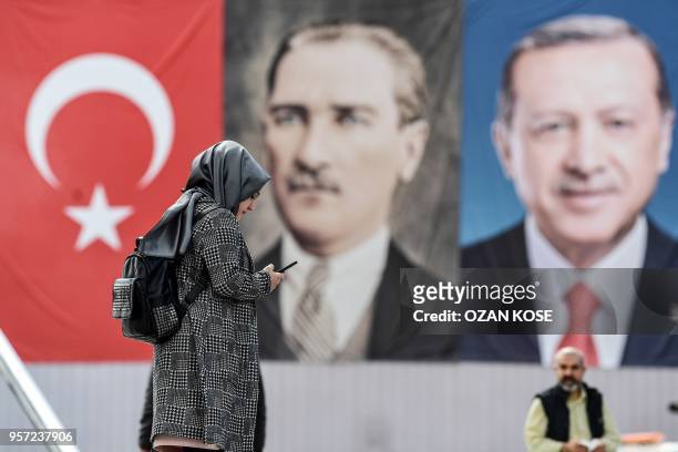 Woman stands in front of the portraits of Turkish President Recep Tayyip Erdogan and founder of modern Turkey Mustafa Kemal Ataturk , on May 11, 2018...