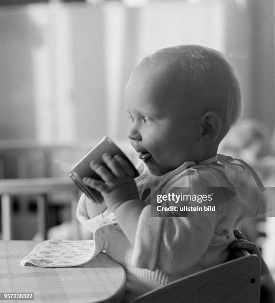 Ein kleines Kind beim Trinken an einem Tisch in einem Kindergarten in Berlin-Treptow, aufgenommen im August 1968.