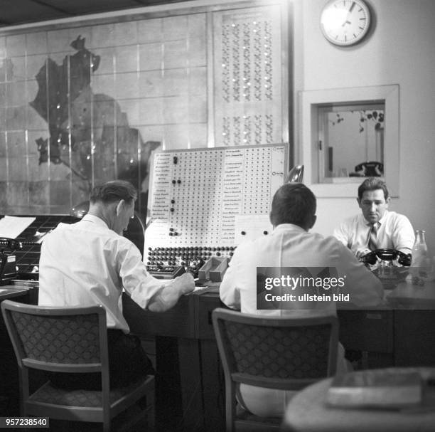 Männer sitzen an Telefonen und einer Schalttafel vor einem Stadtplan von berlin im Rettungsamt Berlin und steuern den Einsatz von Sankra-Fahrzeugen...