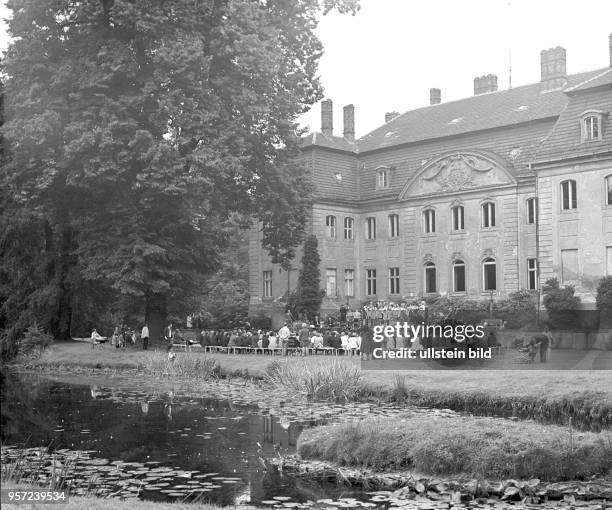 Im Schloßpark Branitz vor dem Fürst-Pückler-Schloß sitzen Besucher und lassen sich von einem Auftritt des Ensemble der Textilarbeiter Cottbus...