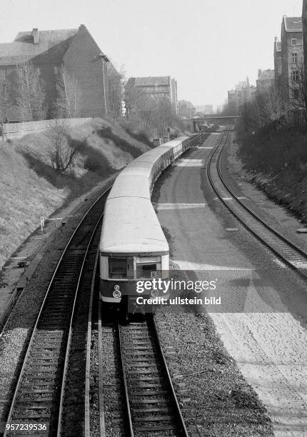 Fahrender S-Bahnzug in Berlin zwischen Mietskasernen aus der Anfangszeit des 19l Jahrhunderts auf der Strecke zwischen den Stationen Prenzlauer Berg...