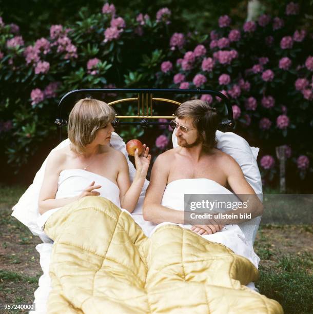 Die Schauspielerin Annekathrin Bürger mit einem Apfel und ihr Mann, der Schauspieler Rolf Römer, in einem Bett im Garten ihres Heims bei Berlin,...