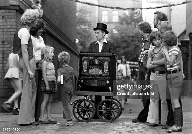 Ein Drehorgelspieler erfreut mit seinem Spiel Groß und Klein, aufgenommen im Juli 1977 im Berliner Stadtbezirk Prenzlauer Berg.