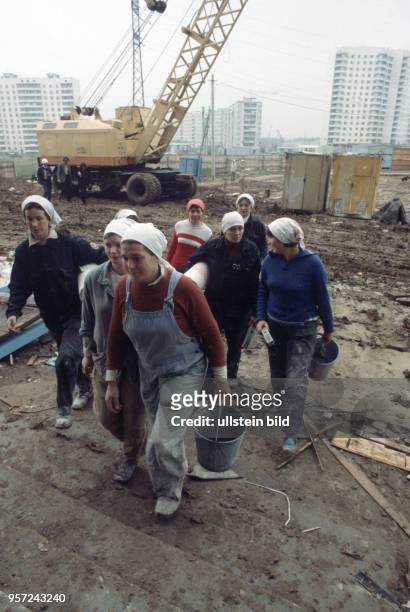 Frauen einer Malerbrigade laufen mit Tapetenrollen und Werkzeug zu ihrer Arbeitsstelle. Das Neubaugebiet Jugo-Zapadnaja im Südwesten Moskaus wurde in...