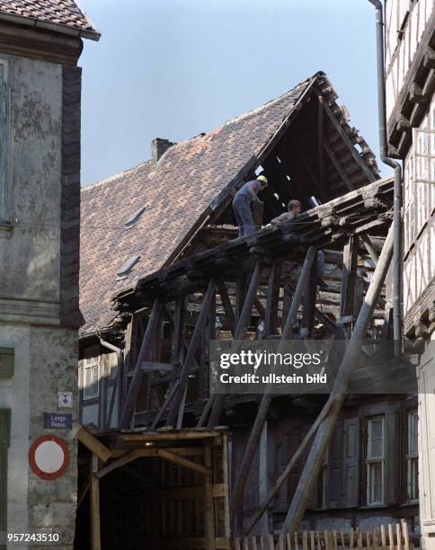 Zwei Arbeiter sind mit der Rekonstruktion eines Fachwerkhauses beschäftigt, aufgenommen 1985 in Quedlinburg. Viele der Häuser waren unbewohnt und...