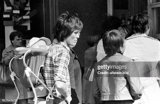 Eine Mutter steht in einer Warteschlange vor einem Geschäft in der Schönhauser Allee, aufgenommen Anfang Juni 1977 im Berliner Stadtbezirk Prenzlauer...