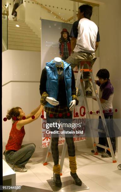 Oktober 2009 / China - Peking/ Dekorateure bei der Arbeit in einem Bekleidungsgerschäft in der sanierten alten Einkaufsstraße Qianmen Dajiie in...