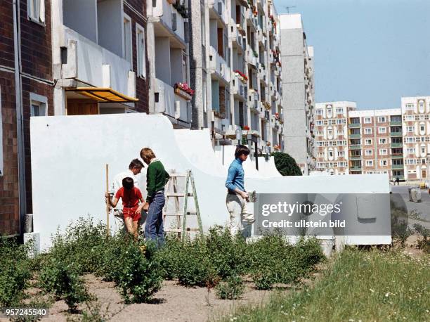 Einwohner bei Verschönerungsarbeiten an ihren Häusern und kleinen Vorgärten im Neubaugebiet Rostock Schmarl, aufgenommen 1979. Die Plattenbausiedlung...
