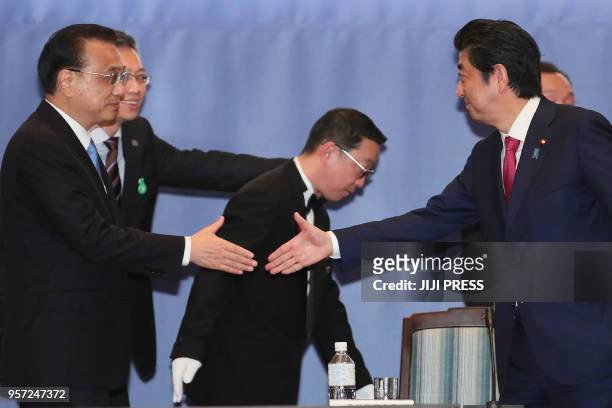 Japan's Prime Minister Shinzo Abe shakes hands with Chinese Premier Li Keqiang during the Japan-China forum in Sapporo, Hokkaido prefecture on May...