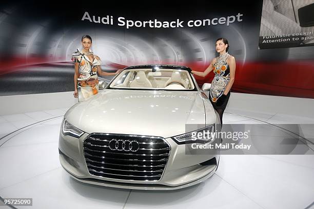 Models pose next to a newly launched Audi car at the 10th Auto expo in New Delhi on Thursday, January 7, 2010.