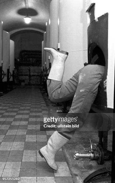 Nur die Füße einer Arbeiterin, die einen Kessel reinigt, ragen aus dem Behälter im VEB Weingroßkellerei Berlin, undatiertes Foto von 1981.