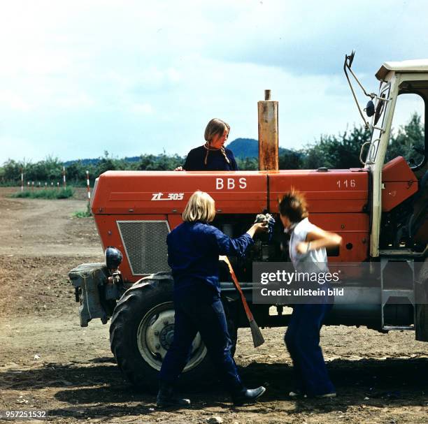 Drei junge Frauen, Schülerinnen an der Betriebsberufsschule des VEG Saatzucht Langenstein arbeiten an einem Traktor ZT 305, undatiertes Foto von...