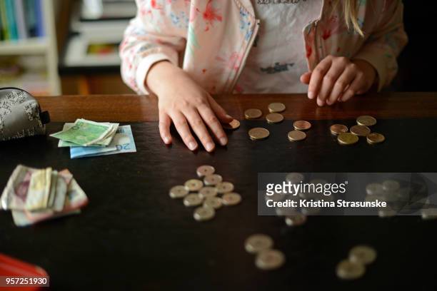 a girl counting money on a wooden table - norway money stock pictures, royalty-free photos & images