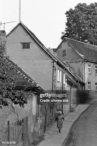 Kleine Häuser ducken sich an die abfallende Straße in der Lutherstadt Eisleben , aufgenommen im September 1981. Hier eine alte Frau auf dem Gehweg....