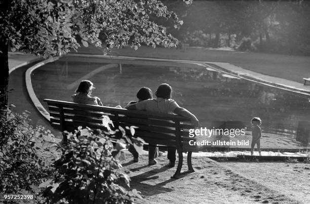 Erwachsene beaufsichtigen 1980 ein Kind in einem Planschbecken im Berliner Bezirk Weißensee und genießen die Sommersonne.