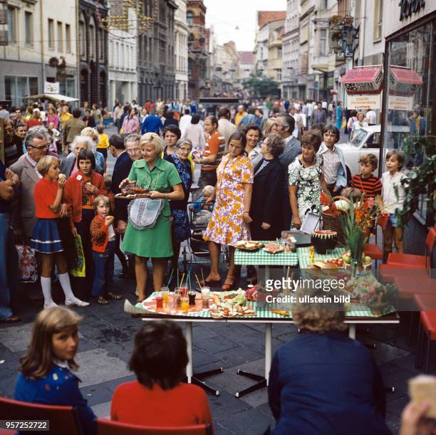 Viele Passanten stehen um mit Speisen gedeckte Tisch bei einer Werbeveranstaltung in der Kröpeliner Straße in Rostock, undatiertes Foto von 1978.