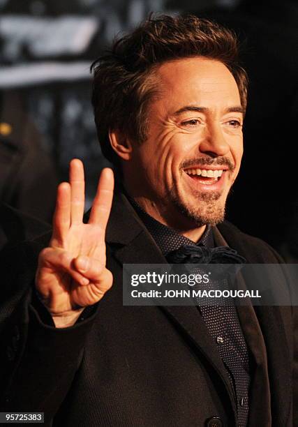 Actor Robert Downey Jr flashes a three-fingered sign as he poses for photographers on the red carpet prior to the German premiere of the film...