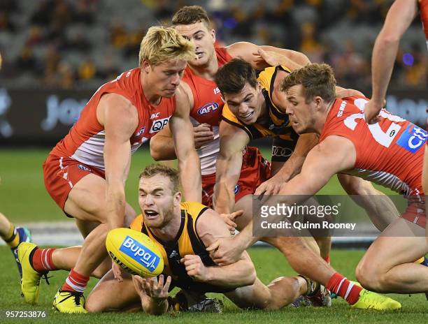 Tom Mitchell of the Hawks handballs whilst being tackled during the round eight AFL match between the Hawthorn Hawks and the Sydney Swans at...