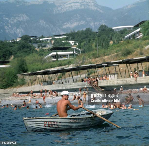 Ein Bademeister im Ruderboot und badende Kinder am Strand des Pionierlagers Artek auf der Krim, aufgenommen im August 1971. Artek war das zentrale...