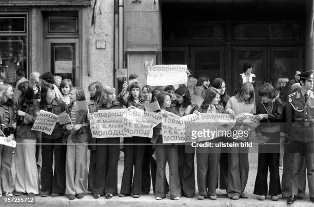 Größtenteils weibliche FDJ-Mitglieder stehen am Straßenrand und grüßen via Transparente die sowjetischen Kosmonauten Bykowski und Aksjonow,...