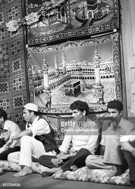 Junge Männer sitzen bei einer Hochzeitsfeierlichkeit in Tripolis unter einem Wandteppich , aufgenommen im September 1979.